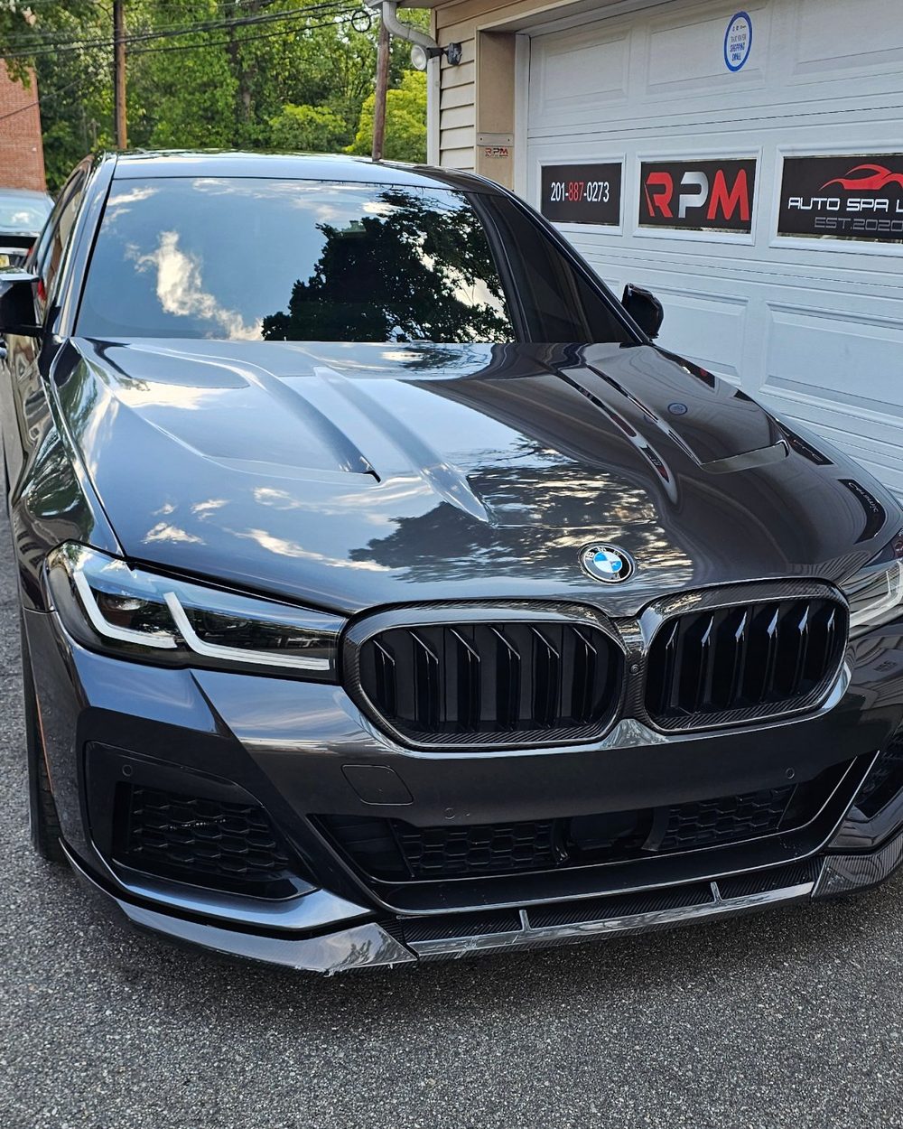 Dark grey BMW 5 Series parked outside the RPM Auto Spa garage door